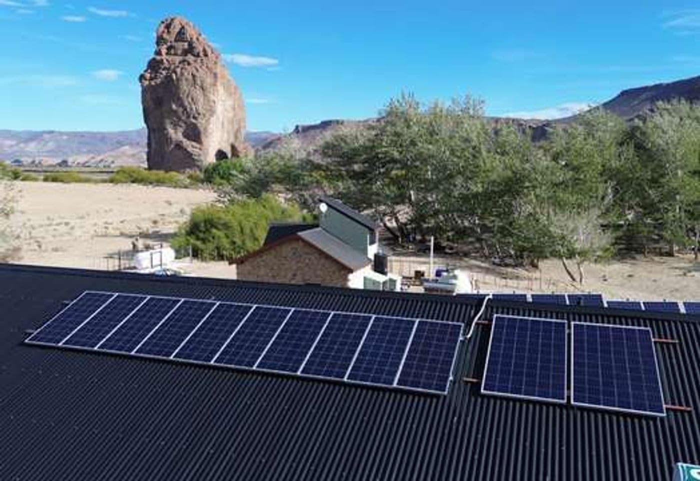 Paneles fotovoltaicos instalados en la estepa patagónica, con un cerro de fondo